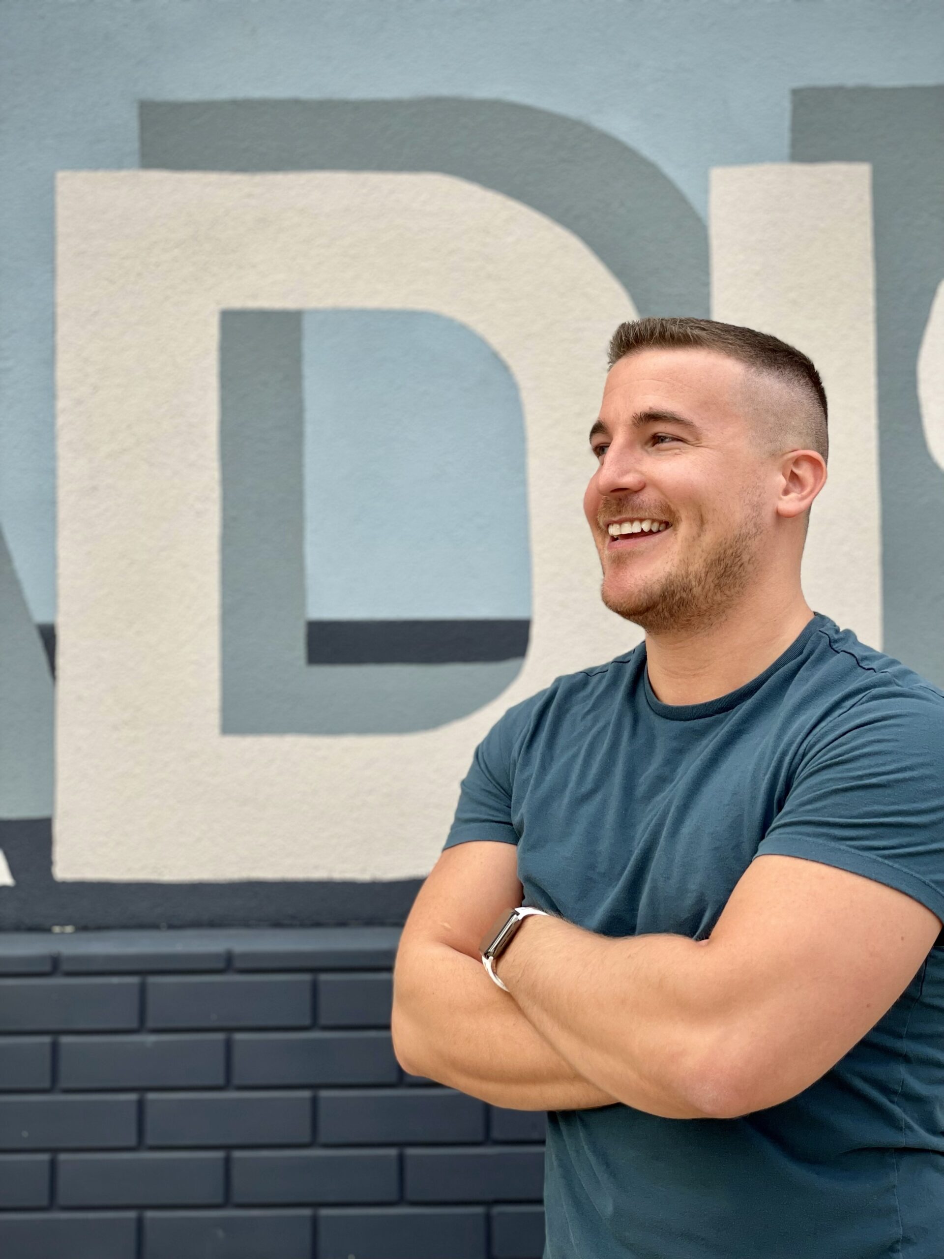 Daniel standing in front of a mural, arms crossed.